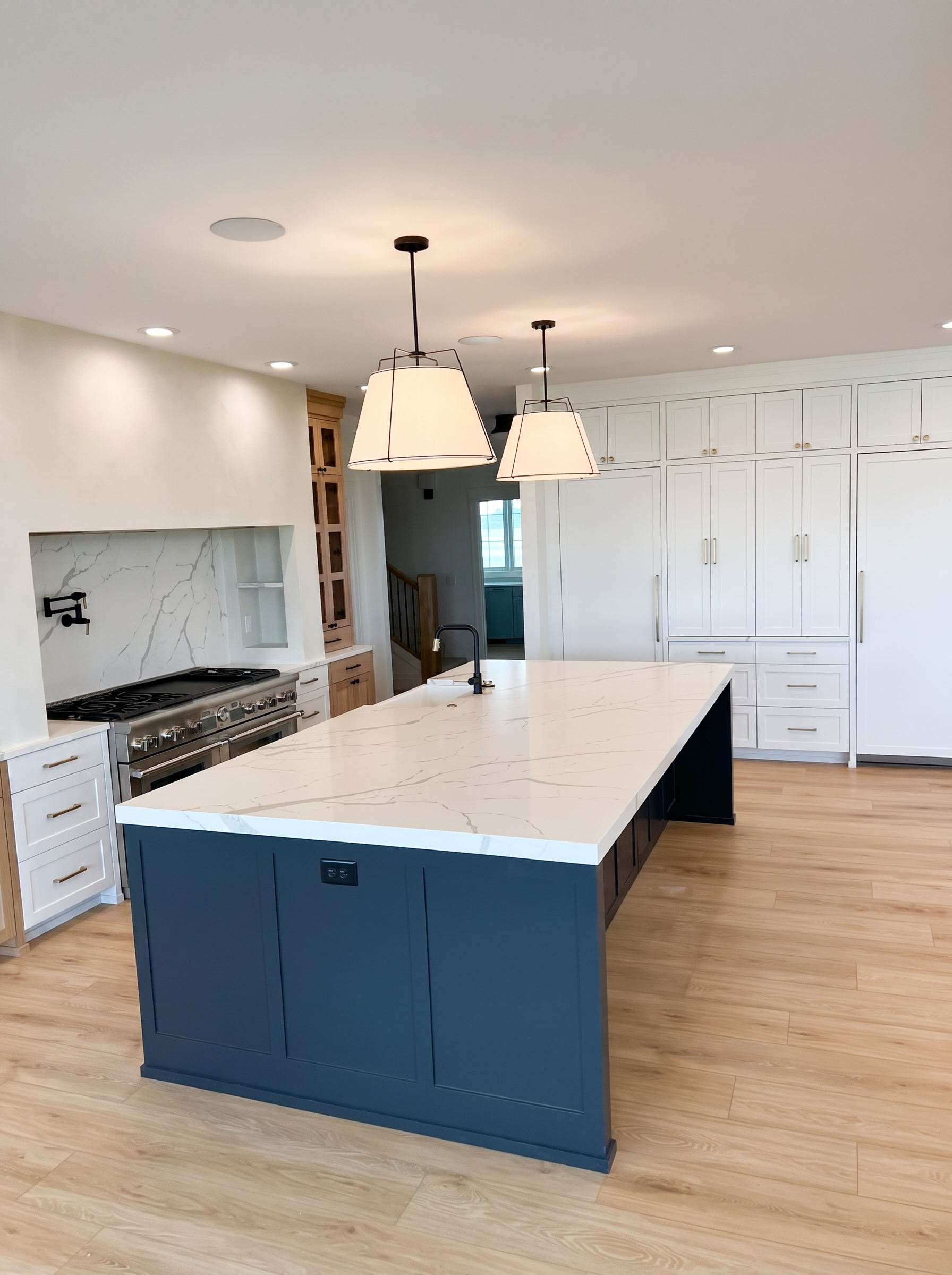 Custom kitchen with navy island and quartz waterfall counters