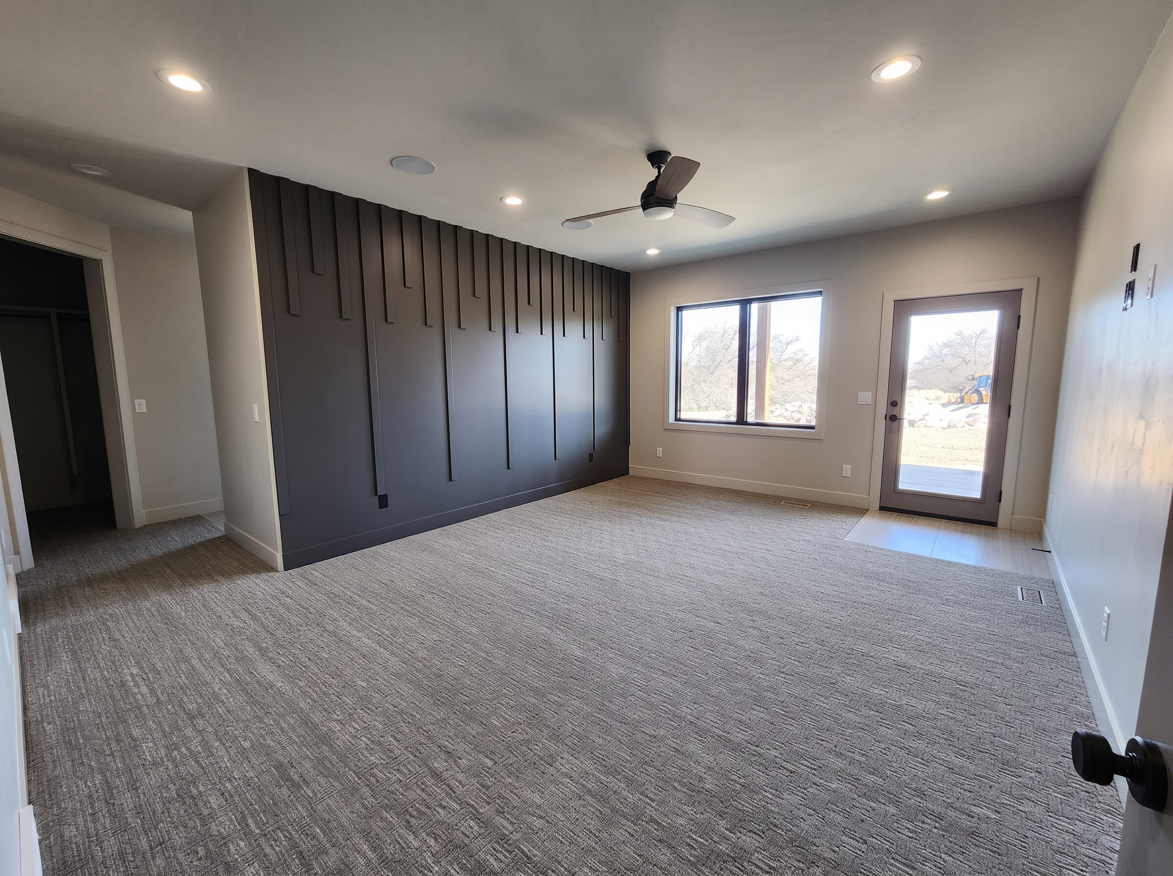 Master bedroom with dark board and batten accent wall and patio door