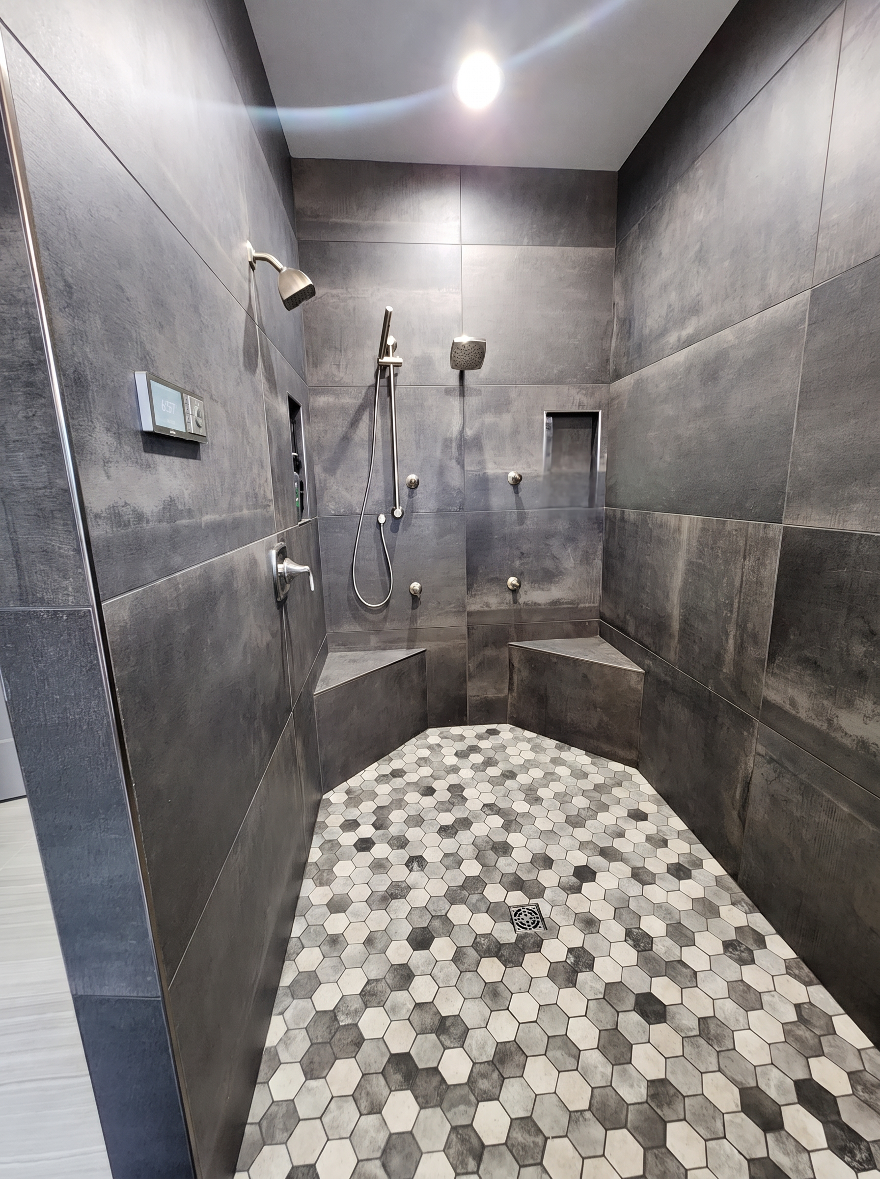 Custom tiled walk-in shower with hex floor tile and bench seating
