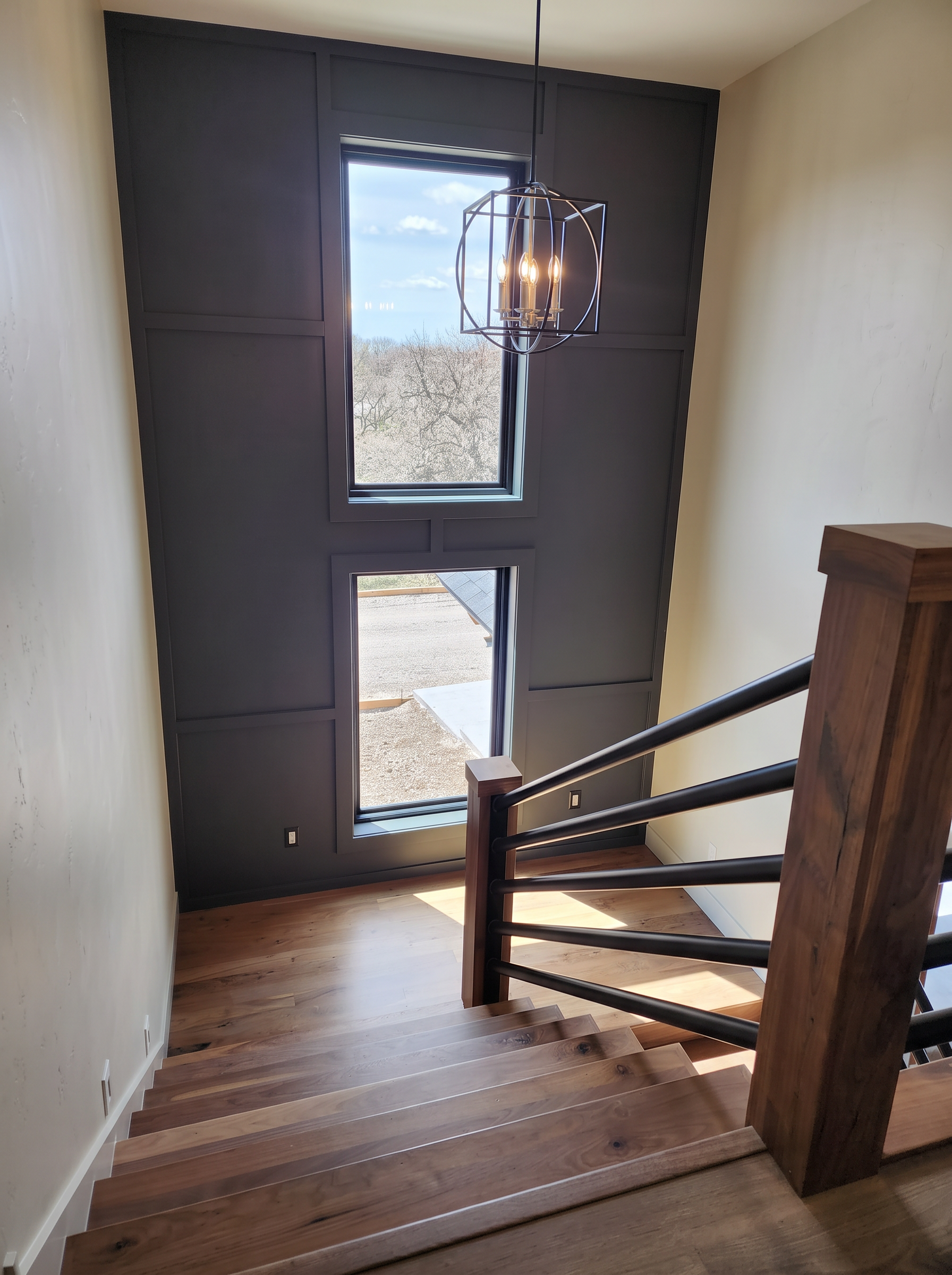 Stair landing with black paneled accent wall and walnut treads