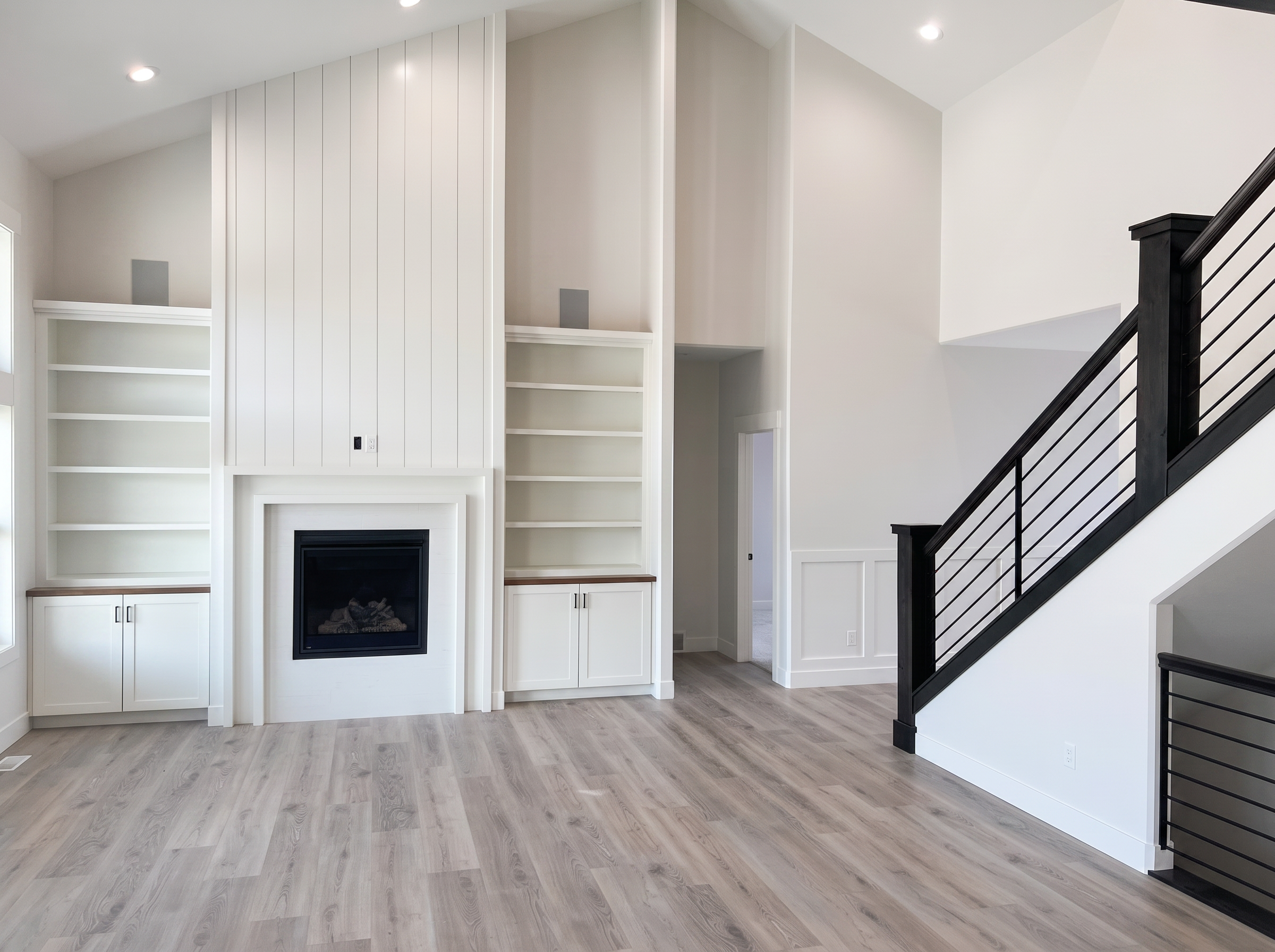 Vaulted great room with shiplap fireplace and built-in shelving